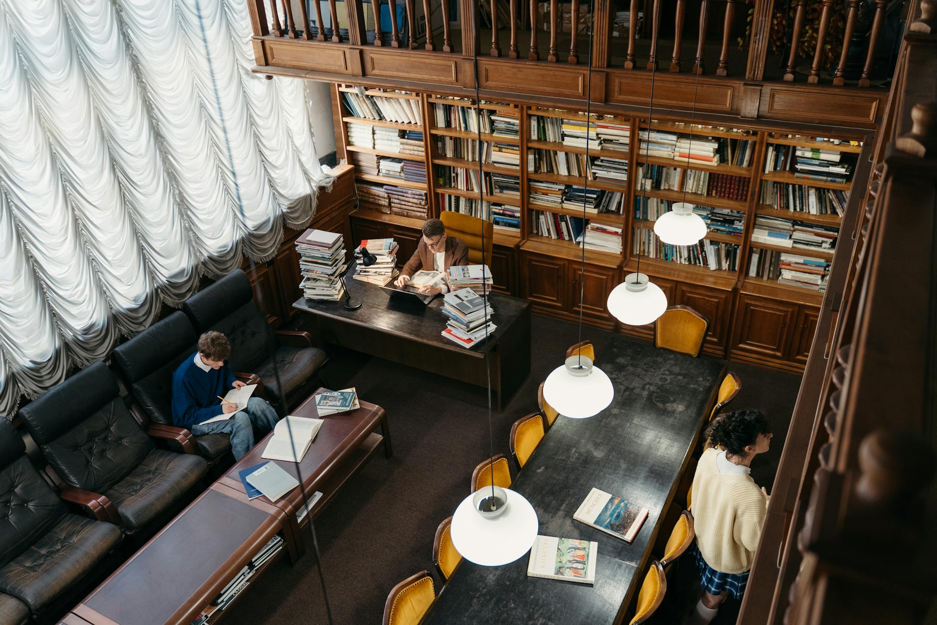 Widok z góry na przytulną bibliotekę z czytającymi i uczącymi się osobami